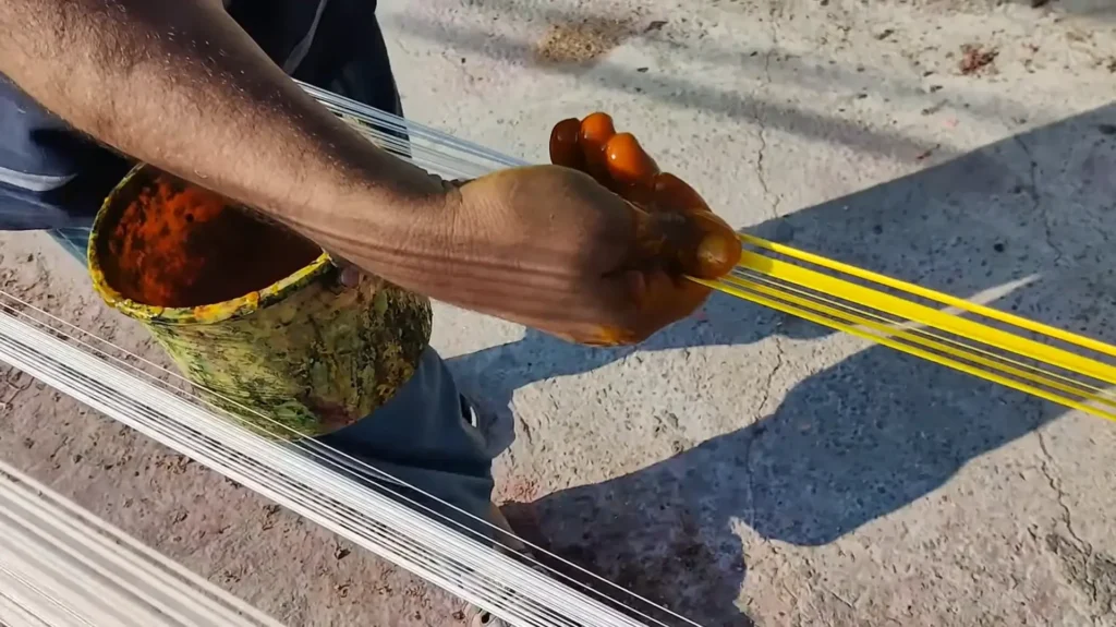 person adding liquid color to thread in process of making dor basantmela